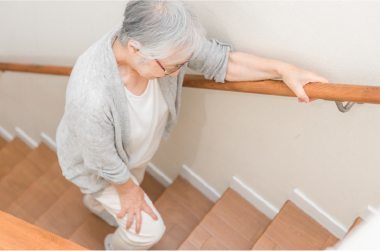 階段をつらそうに昇る高齢女性